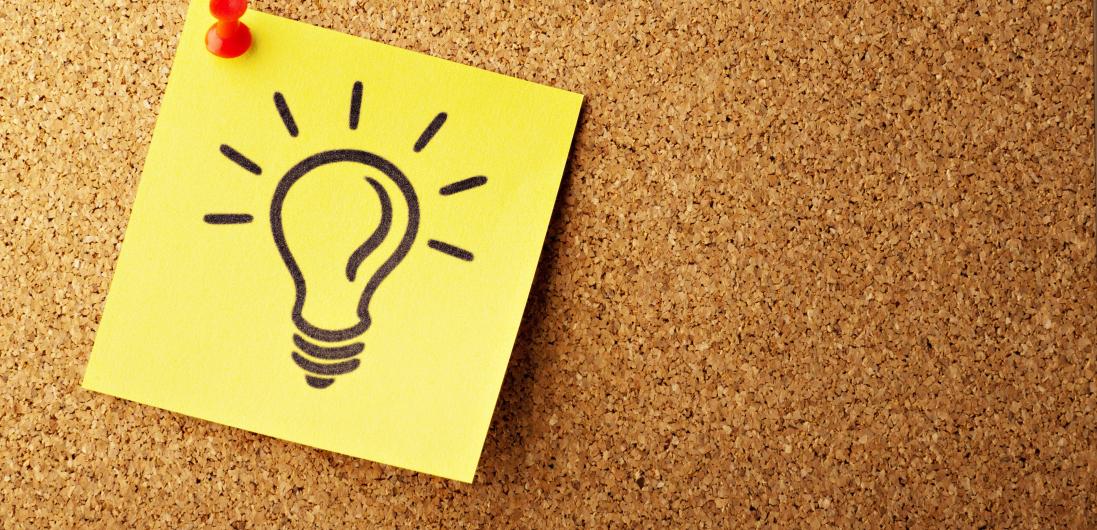 a post note with a light buld on a corkboard